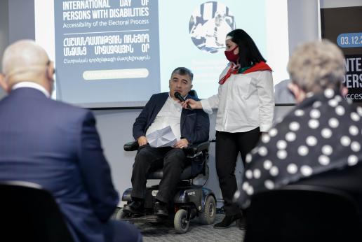 Man in a wheelchair speaking at a conference